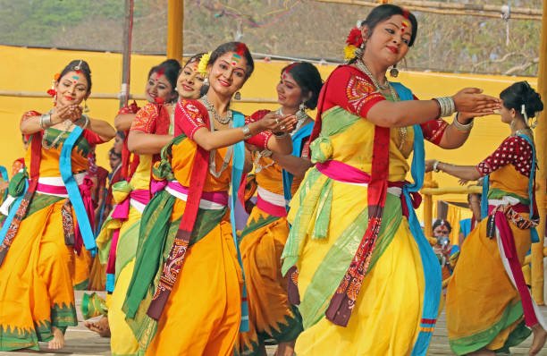 Bengali women in yellow sarees marking Holi traditions with Basant Utsav