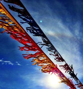 Colorful streamers dance in the wind against a bright blue sky, capturing the essence of a sunny day.